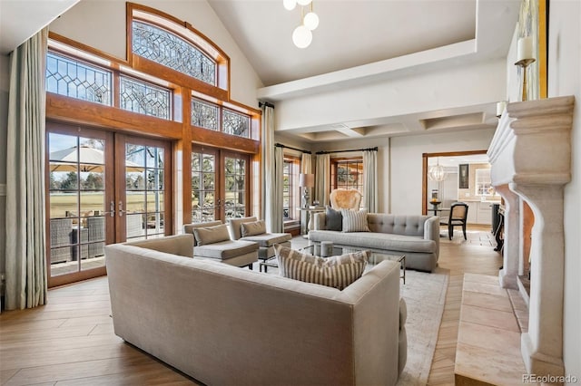 living room with high vaulted ceiling, french doors, a healthy amount of sunlight, and light wood finished floors