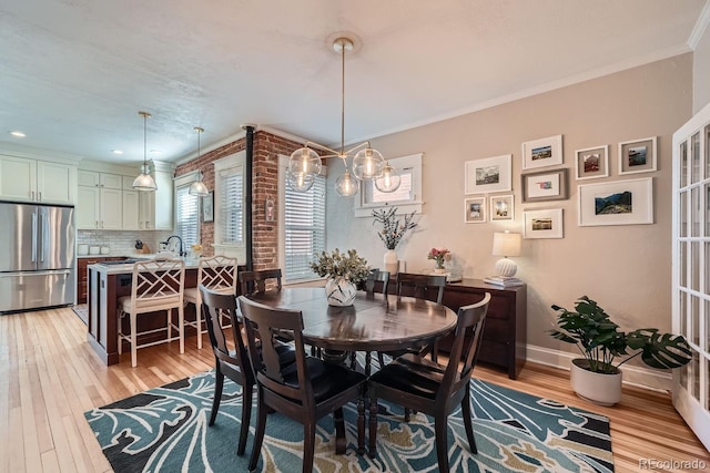 dining space featuring baseboards, light wood-style flooring, and crown molding