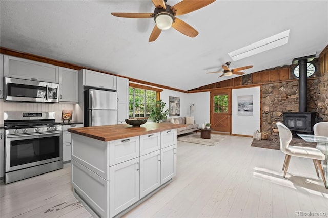 41 Silver Spruce, Boulder, CO 80302 - kitchen featuring appliances with stainless steel finishes, wood counters, open floor plan, a wood stove, and a ceiling fan