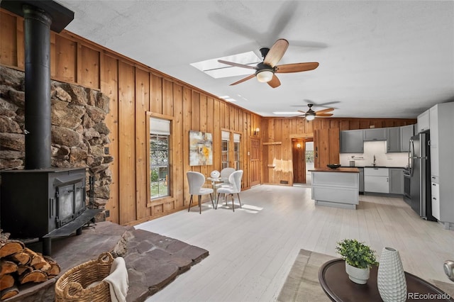 41 Silver Spruce, Boulder, CO 80302 - living area with wooden walls, a wood stove, light wood finished floors, and a ceiling fan