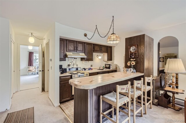 kitchen featuring light carpet, a breakfast bar area, kitchen peninsula, white appliances, and dark brown cabinets