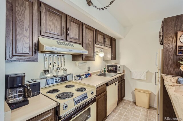 kitchen with sink, dark brown cabinetry, white appliances, and light tile patterned floors