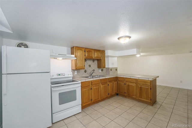 kitchen featuring sink, backsplash, tile counters, kitchen peninsula, and white appliances