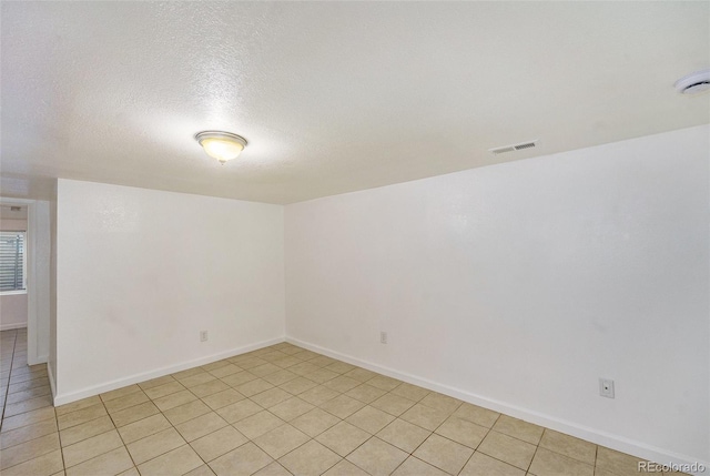 tiled empty room featuring a textured ceiling