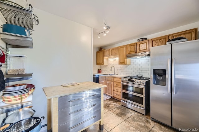 kitchen featuring rail lighting, backsplash, sink, appliances with stainless steel finishes, and light tile patterned flooring