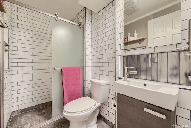 bathroom featuring tiled shower, vanity, toilet, and tile walls