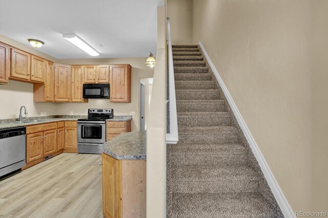 kitchen featuring sink, decorative light fixtures, light brown cabinetry, appliances with stainless steel finishes, and light hardwood / wood-style floors