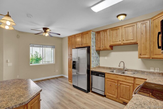 kitchen featuring ceiling fan, appliances with stainless steel finishes, light wood-type flooring, sink, and decorative light fixtures