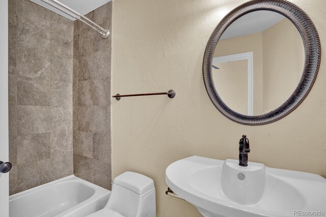 full bathroom with tiled shower / bath, sink, and toilet