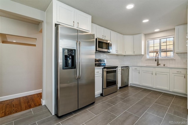 5500 Holland Dr, Arvada, CO 80002 - kitchen with stainless steel appliances, a sink, white cabinets, backsplash, and recessed lighting