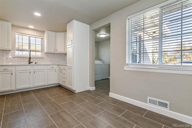 5500 Holland Dr, Arvada, CO 80002 - kitchen with washing machine and dryer, decorative backsplash, white cabinets, light countertops, and baseboards