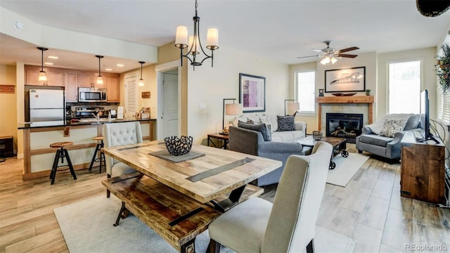 dining area with a fireplace, ceiling fan with notable chandelier, a healthy amount of sunlight, and sink