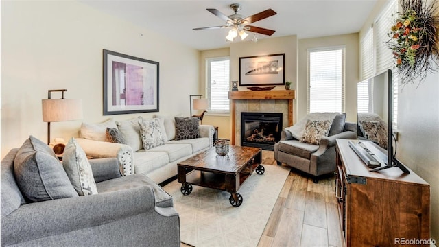 living room featuring ceiling fan, a fireplace, light hardwood / wood-style floors, and plenty of natural light