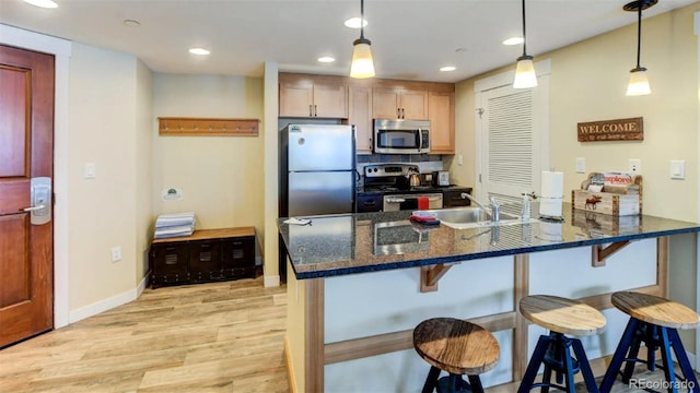 kitchen with a kitchen bar, backsplash, pendant lighting, and stainless steel appliances