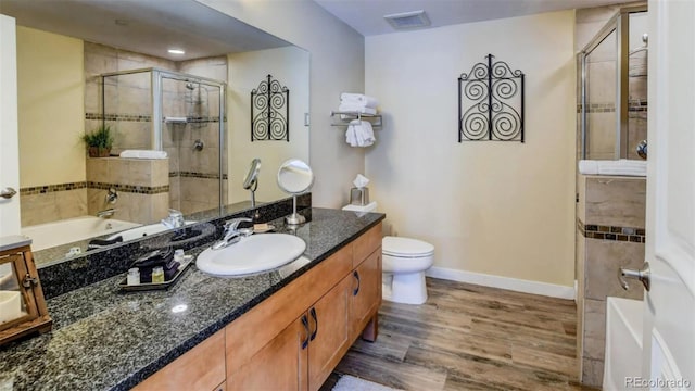 full bathroom with plus walk in shower, hardwood / wood-style floors, vanity, and toilet