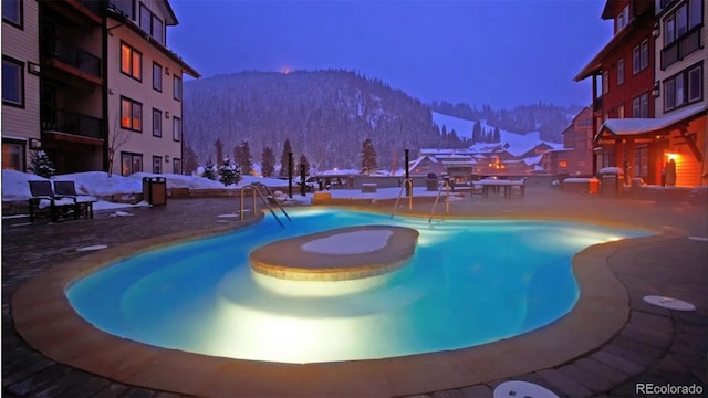 pool at dusk with a mountain view and a patio