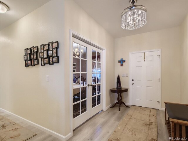 foyer with light hardwood / wood-style floors, an inviting chandelier, and french doors