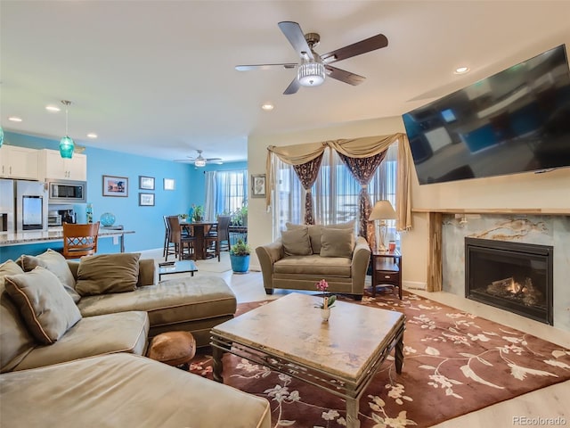 living room with ceiling fan and a high end fireplace