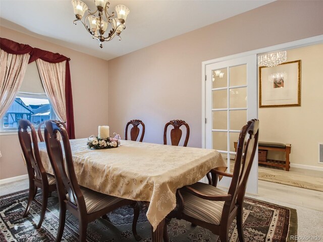 dining area with hardwood / wood-style floors and an inviting chandelier