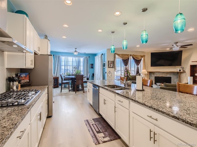 kitchen featuring white cabinetry, sink, a high end fireplace, decorative light fixtures, and appliances with stainless steel finishes