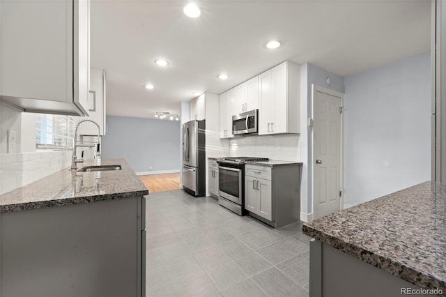 kitchen with white cabinets, sink, dark stone countertops, tasteful backsplash, and stainless steel appliances