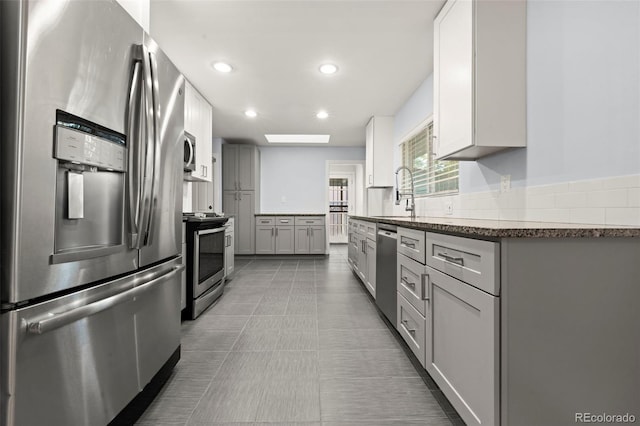 kitchen featuring appliances with stainless steel finishes, gray cabinets, dark tile patterned floors, and sink