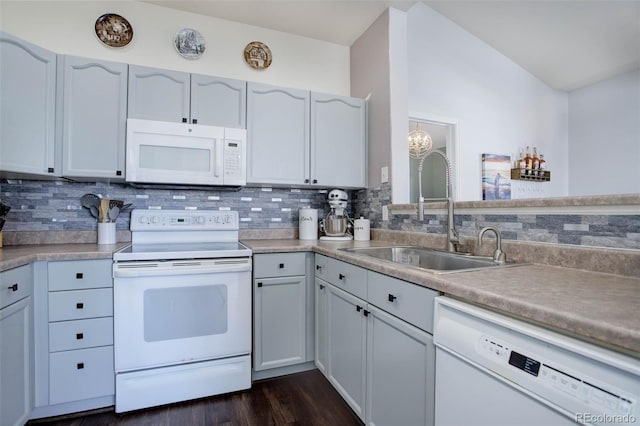 kitchen with tasteful backsplash, sink, white appliances, and dark wood-type flooring