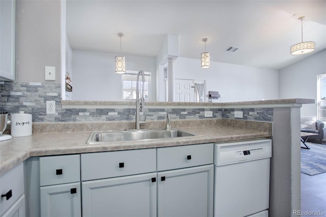 kitchen featuring tasteful backsplash, white dishwasher, pendant lighting, sink, and kitchen peninsula