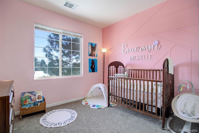 bedroom with a nursery area and carpet flooring