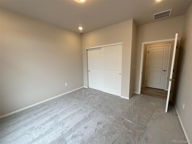 unfurnished bedroom with baseboards, carpet floors, a closet, and visible vents