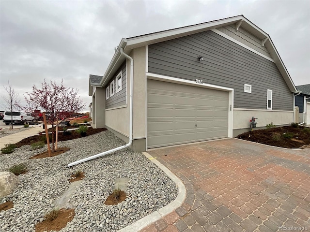 view of side of home featuring a garage and decorative driveway