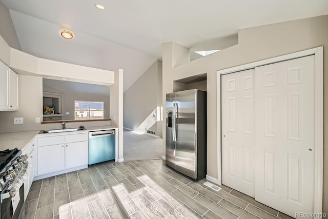 kitchen featuring white cabinetry, sink, vaulted ceiling, and appliances with stainless steel finishes