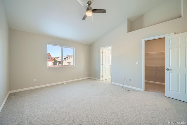 unfurnished bedroom with a walk in closet, high vaulted ceiling, light carpet, a closet, and ceiling fan