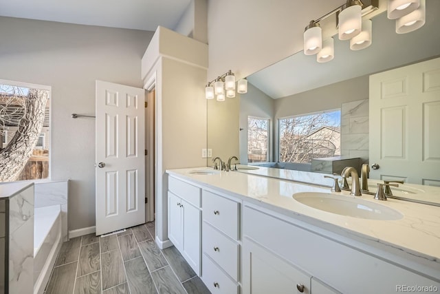 bathroom with a tub to relax in, vanity, and lofted ceiling