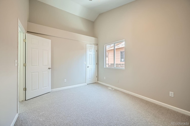 carpeted empty room with vaulted ceiling