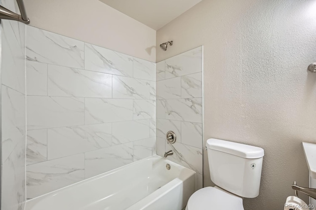 bathroom with tiled shower / bath combo and toilet