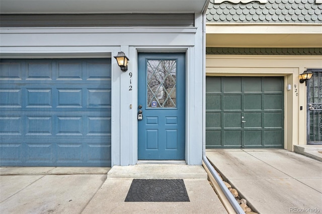 entrance to property featuring a garage, concrete driveway, and stucco siding