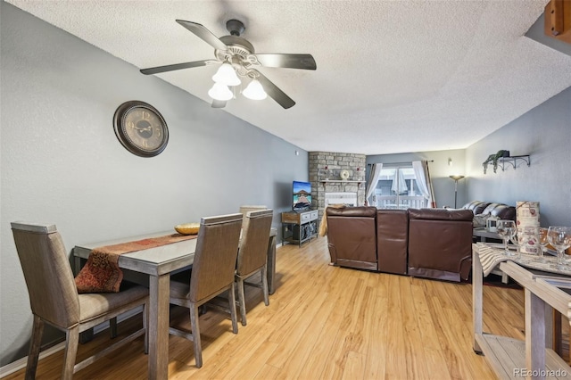 dining space featuring a ceiling fan, light wood-style flooring, and a textured ceiling