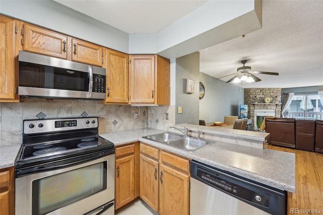 kitchen with decorative backsplash, open floor plan, a peninsula, stainless steel appliances, and a sink