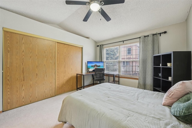 carpeted bedroom featuring vaulted ceiling, a closet, a textured ceiling, and a ceiling fan