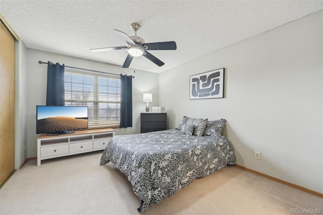 carpeted bedroom featuring baseboards, a ceiling fan, and a textured ceiling