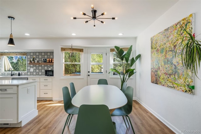 dining space featuring an inviting chandelier, light hardwood / wood-style flooring, and sink