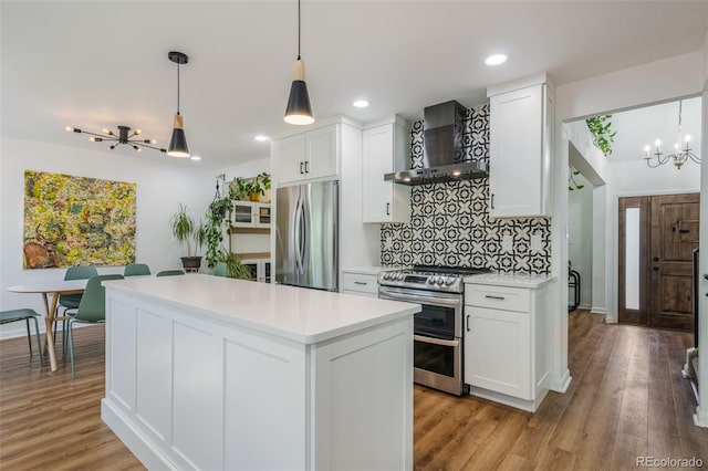 kitchen with wall chimney range hood, appliances with stainless steel finishes, light wood-type flooring, and white cabinets