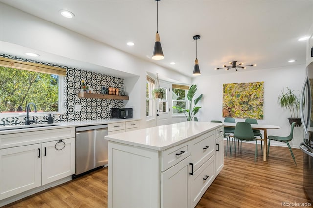 kitchen with stainless steel dishwasher, white cabinets, and light hardwood / wood-style flooring