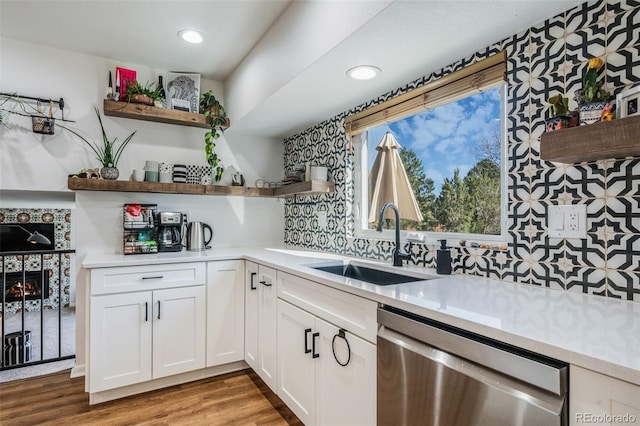 kitchen featuring light hardwood / wood-style flooring, sink, stainless steel dishwasher, white cabinetry, and tasteful backsplash