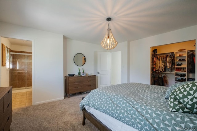 carpeted bedroom featuring a spacious closet, ensuite bathroom, a closet, and a chandelier