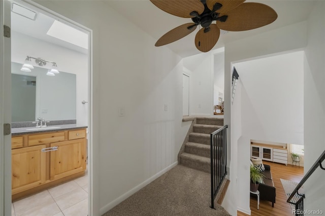 stairway with sink, carpet, and ceiling fan