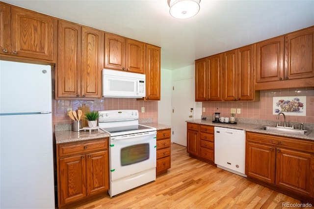 2744 S Newton Way, Denver, CO 80236 - kitchen featuring white appliances, a sink, brown cabinetry, tasteful backsplash, and light wood finished floors