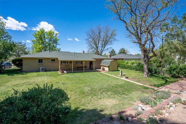 2744 S Newton Way, Denver, CO 80236 - rear view of property with a storage shed, a patio area, an outbuilding, a lawn, and brick siding