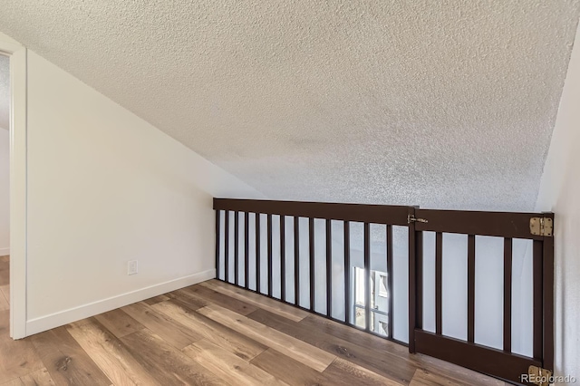 staircase featuring a textured ceiling, wood finished floors, and baseboards